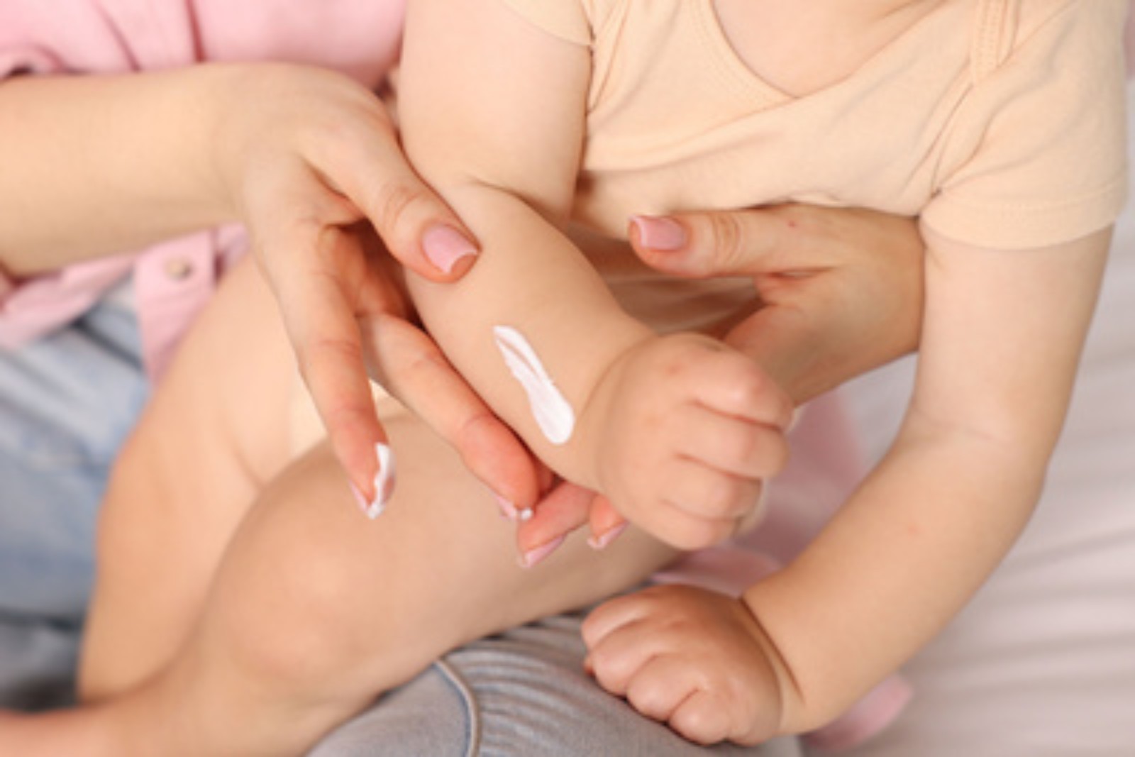 Parent applying emollient cream to a child's arm as part of a daily skin routine