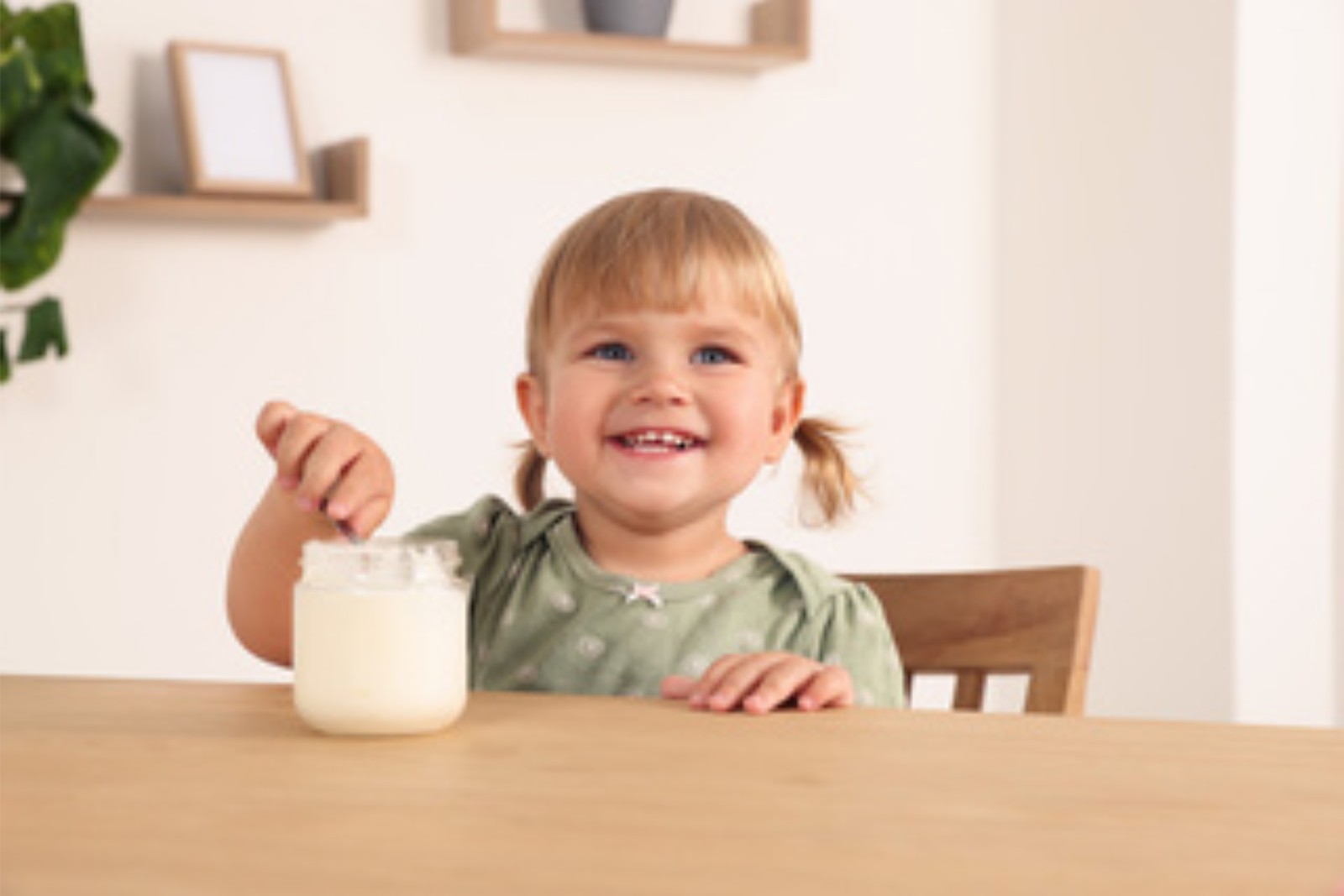 Young child eating yoghurt at the kitchen table