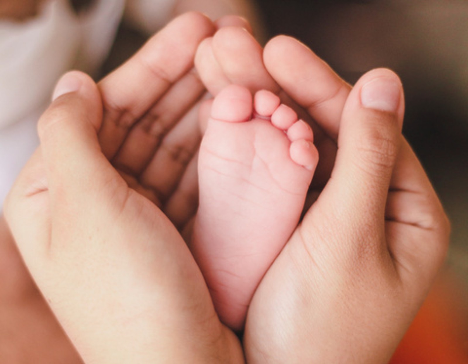 Adult hands cradling a baby's foot, gentle skin care for a child with eczema